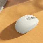 Mouse Bluetooth Logitech M196 berwarna putih di atas meja kayu.