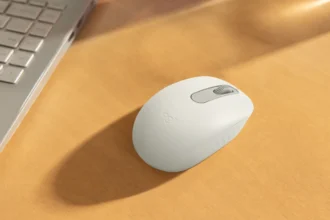 Mouse Bluetooth Logitech M196 berwarna putih di atas meja kayu.