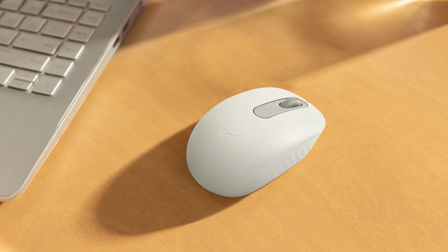Mouse Bluetooth Logitech M196 berwarna putih di atas meja kayu.
